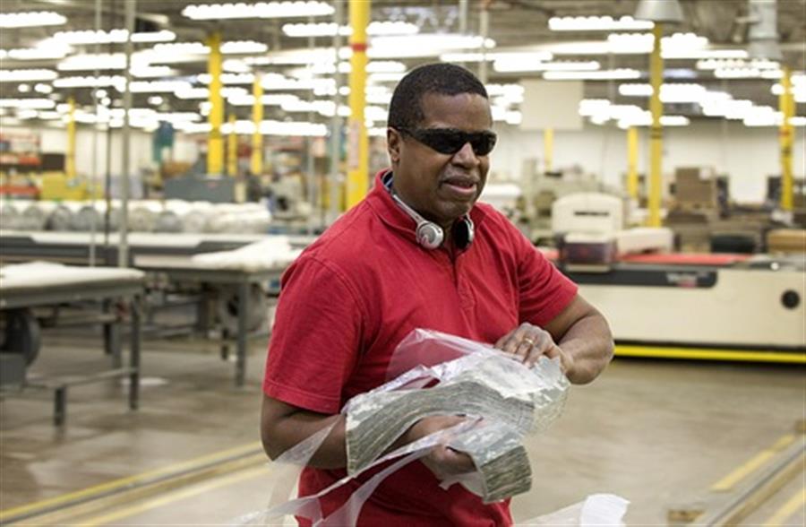 A man transporting fabric in a manufacturing plant.